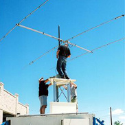 Two men errecting a large portable mast.